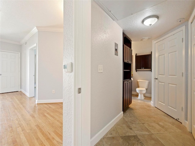 hall featuring light hardwood / wood-style floors, a textured ceiling, and crown molding