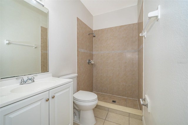 bathroom with vanity, tiled shower, toilet, and tile patterned floors