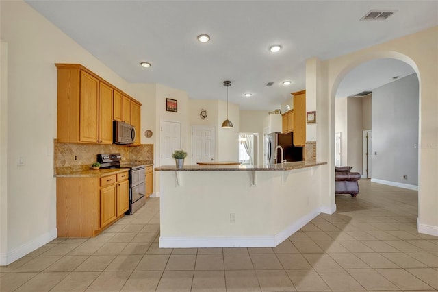 kitchen with light stone counters, appliances with stainless steel finishes, kitchen peninsula, and light tile patterned floors