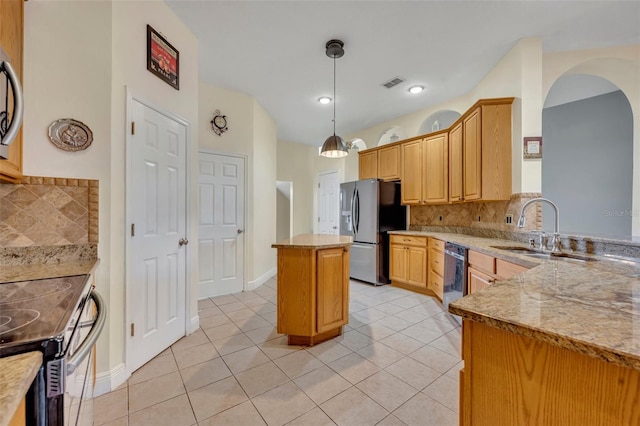 kitchen with appliances with stainless steel finishes, sink, a center island, light stone counters, and light tile patterned floors