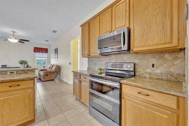 kitchen featuring light stone countertops, appliances with stainless steel finishes, backsplash, and light tile patterned floors