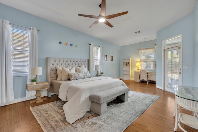 bedroom featuring access to exterior, multiple windows, wood-type flooring, and ceiling fan