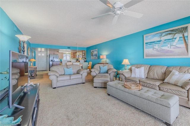 living room with a textured ceiling, light colored carpet, and ceiling fan