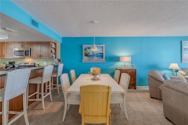 dining area featuring light carpet and a textured ceiling