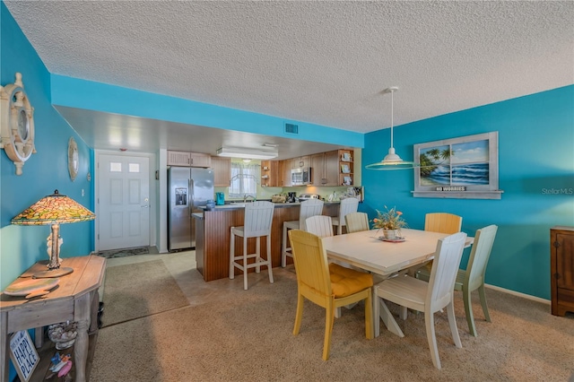 carpeted dining room featuring a textured ceiling and sink