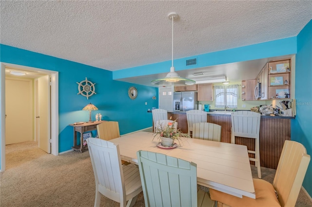 dining room with light carpet, a textured ceiling, and sink