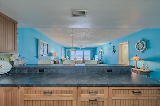 5501 S Atlantic Ave Unit 307, New Smyrna Beach, FL 32169 - kitchen featuring dark countertops, ceiling fan, a textured ceiling, a peninsula, and visible vents
