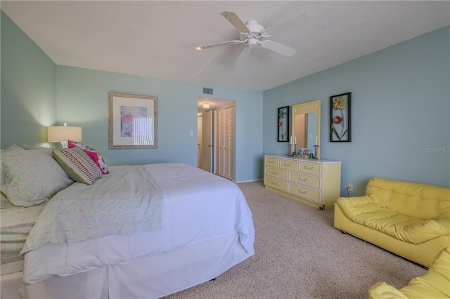 carpeted bedroom with a textured ceiling, a closet, and ceiling fan