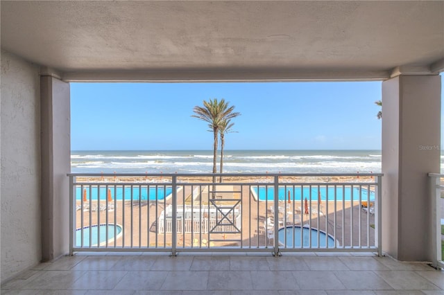 balcony featuring a water view and a beach view