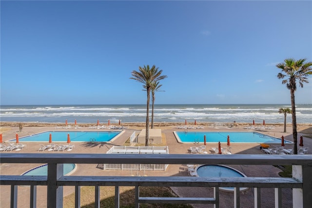 view of pool with a water view, a patio area, and a beach view