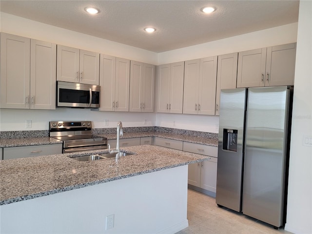 kitchen with stone countertops, stainless steel appliances, a textured ceiling, and sink