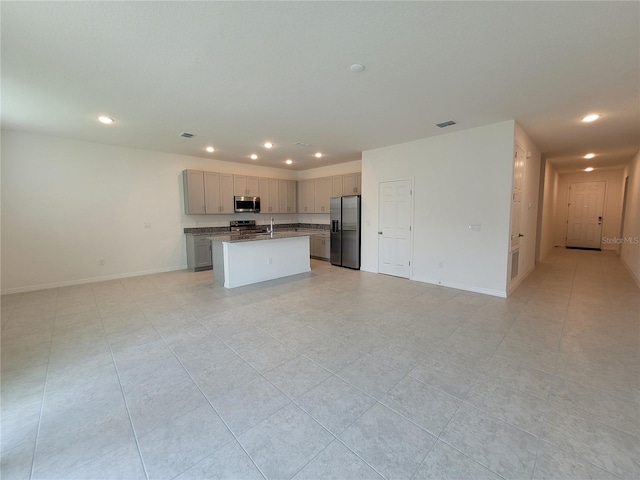 kitchen featuring stainless steel appliances, light tile patterned floors, an island with sink, and gray cabinets