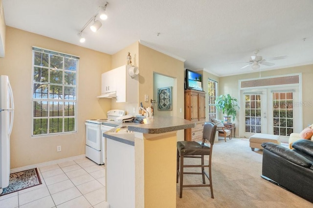 kitchen with white appliances, white cabinetry, a breakfast bar, and plenty of natural light