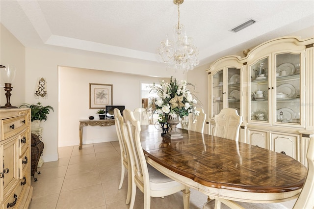 tiled dining space with a textured ceiling and a chandelier