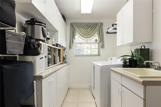 washroom with cabinets, light tile patterned floors, a textured ceiling, independent washer and dryer, and sink