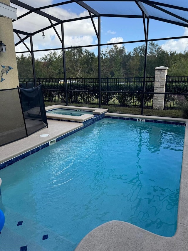 view of pool with an in ground hot tub and glass enclosure