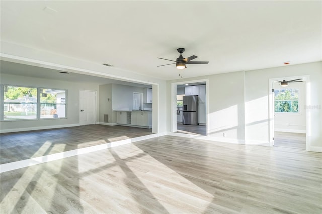 unfurnished room with light wood-type flooring, a healthy amount of sunlight, and ceiling fan