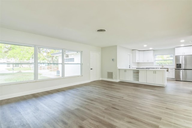 unfurnished living room with light hardwood / wood-style floors and sink