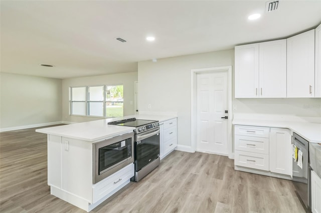 kitchen featuring appliances with stainless steel finishes, kitchen peninsula, white cabinets, and light wood-type flooring