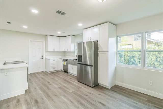 kitchen with light hardwood / wood-style flooring, white cabinets, and stainless steel appliances