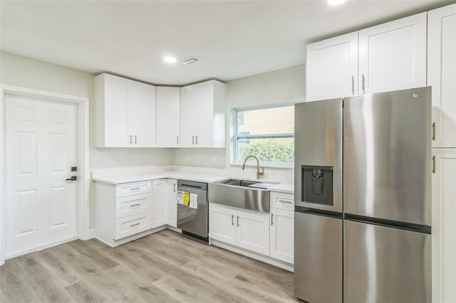 kitchen featuring light hardwood / wood-style floors, appliances with stainless steel finishes, sink, and white cabinets