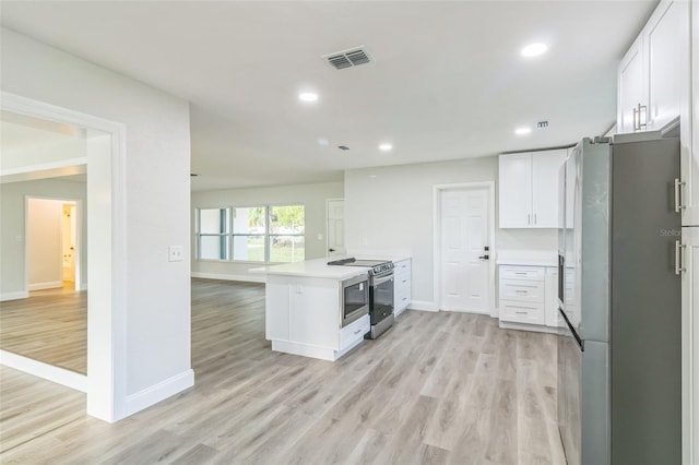 kitchen with light hardwood / wood-style floors, stainless steel appliances, kitchen peninsula, and white cabinets