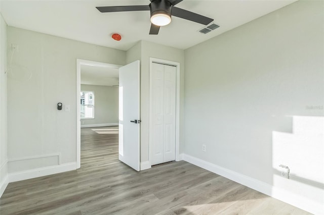 unfurnished bedroom featuring light hardwood / wood-style floors, a closet, and ceiling fan