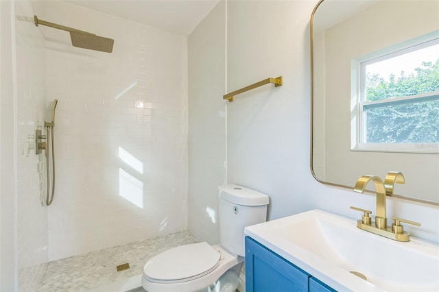 bathroom with toilet, vanity, and a tile shower