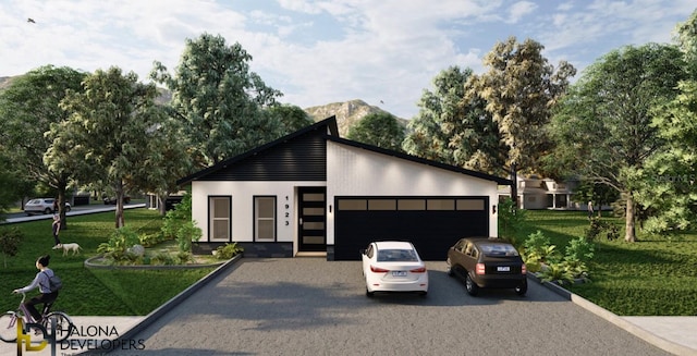 view of front of home with a garage, a front lawn, and a mountain view