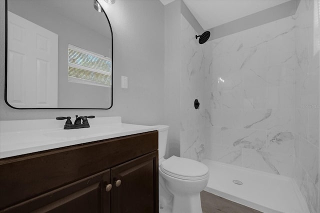 bathroom with a tile shower, vanity, and toilet