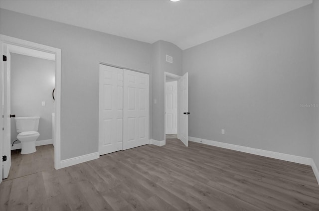 unfurnished bedroom featuring light hardwood / wood-style flooring, a closet, and ensuite bath