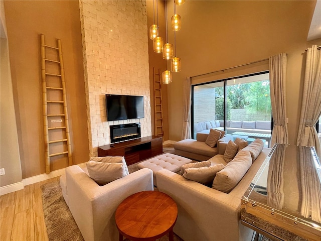 living room featuring hardwood / wood-style floors, a stone fireplace, and a towering ceiling