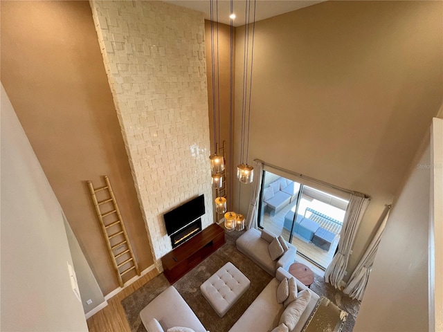 living room featuring a large fireplace, wood-type flooring, and a high ceiling