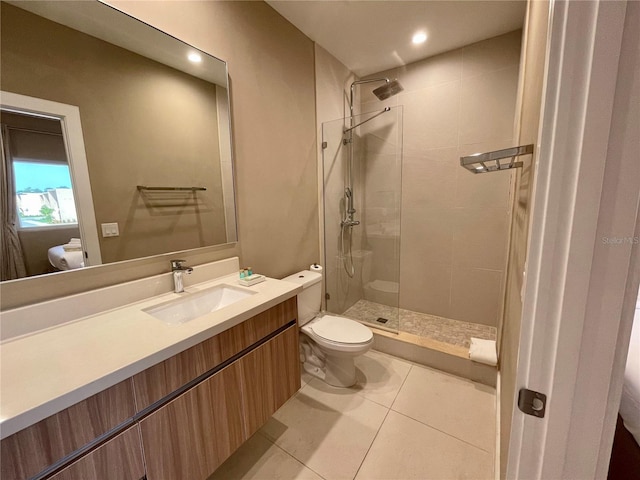 bathroom with vanity, tile patterned flooring, toilet, and tiled shower