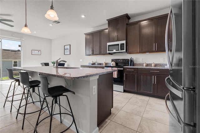 kitchen featuring sink, an island with sink, decorative light fixtures, and stainless steel appliances