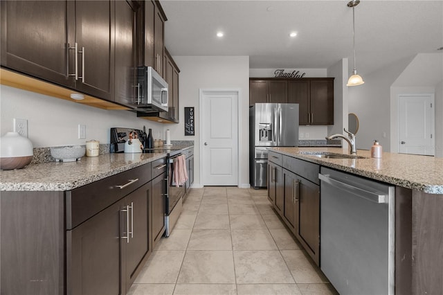 kitchen with hanging light fixtures, an island with sink, appliances with stainless steel finishes, dark brown cabinetry, and sink