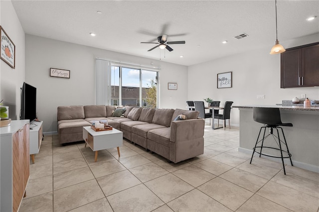 tiled living room with ceiling fan and a textured ceiling