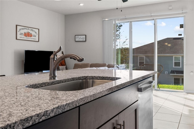 kitchen with ceiling fan, light tile patterned flooring, light stone countertops, and sink