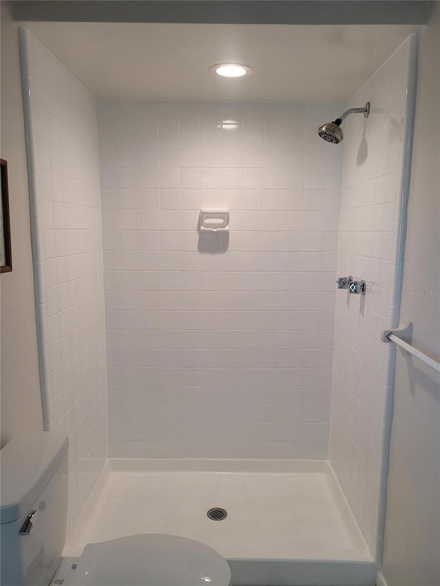 bathroom with a tile shower and toilet