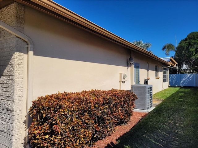 view of side of home with central AC and a lawn