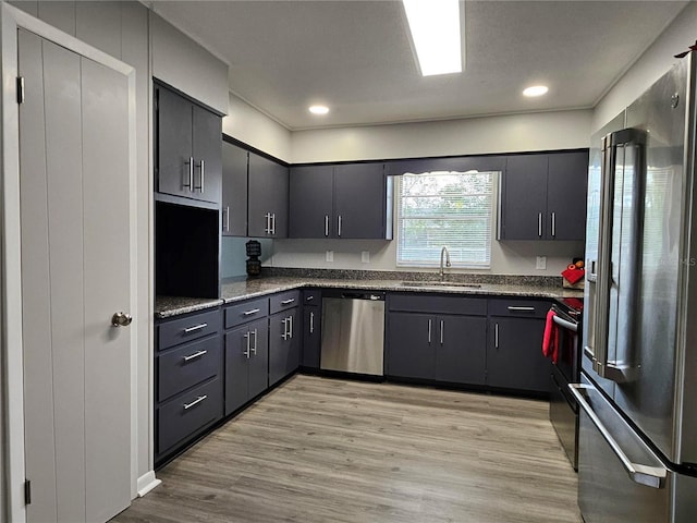 kitchen with stainless steel appliances, sink, and light hardwood / wood-style flooring