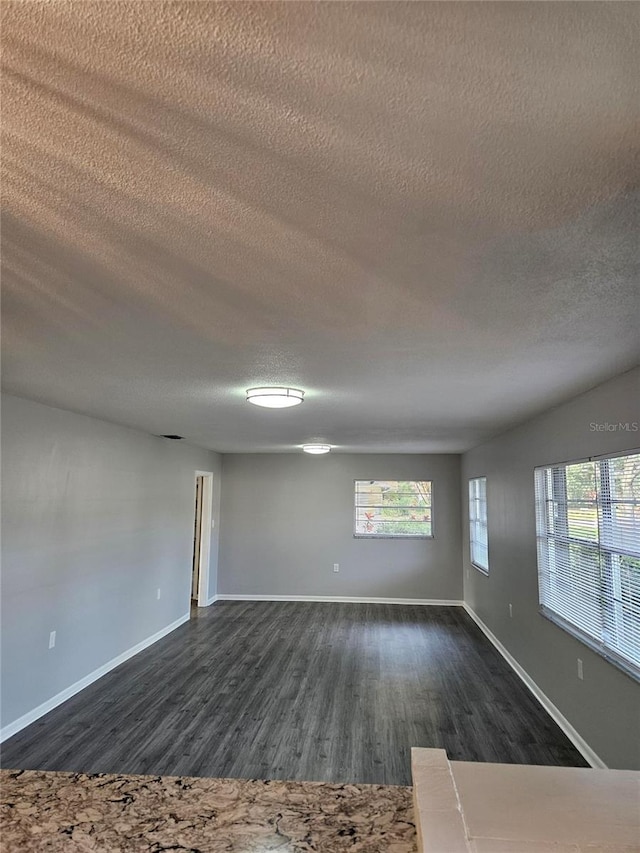 unfurnished room featuring dark hardwood / wood-style flooring and a textured ceiling