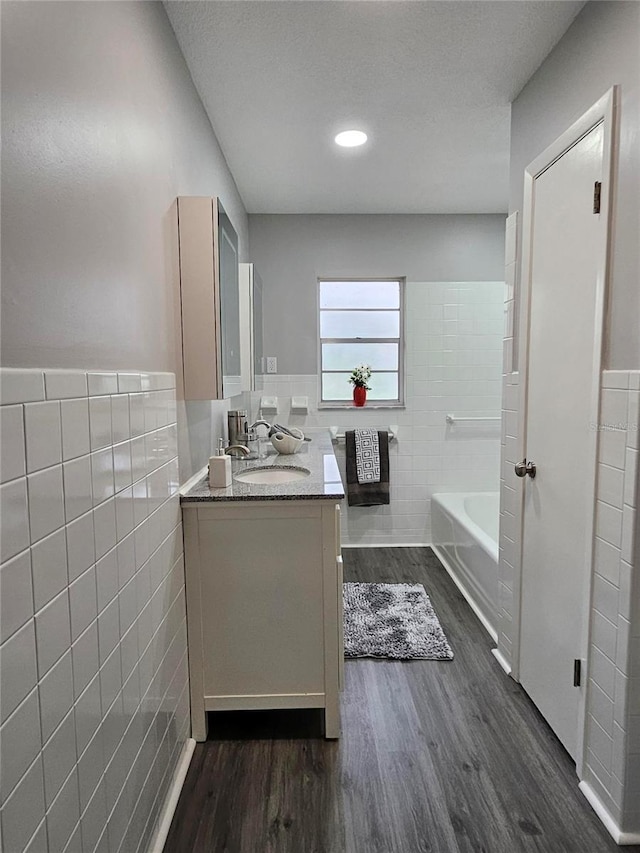 bathroom featuring wood-type flooring, a bathtub, and tile walls