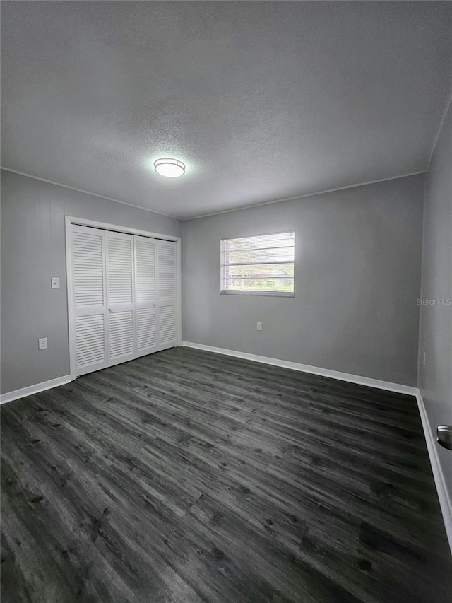 unfurnished bedroom featuring dark hardwood / wood-style flooring, a closet, and a textured ceiling