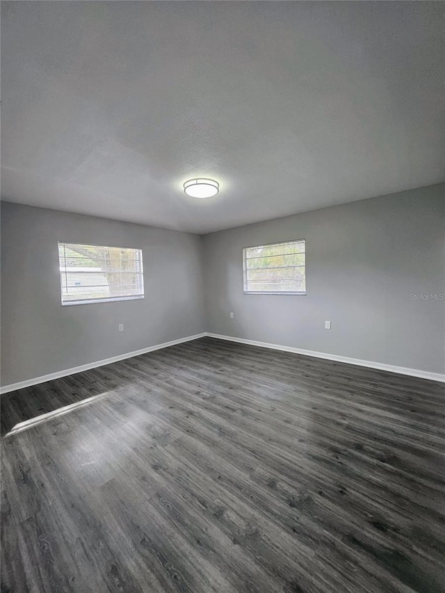 unfurnished room with dark hardwood / wood-style flooring and a textured ceiling