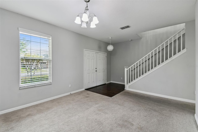 carpeted entryway with a chandelier