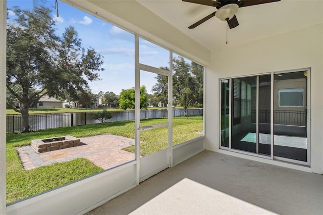 unfurnished sunroom with ceiling fan, a healthy amount of sunlight, and a water view