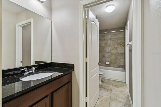 full bathroom featuring tile patterned floors, vanity, a textured ceiling, tiled shower / bath combo, and toilet