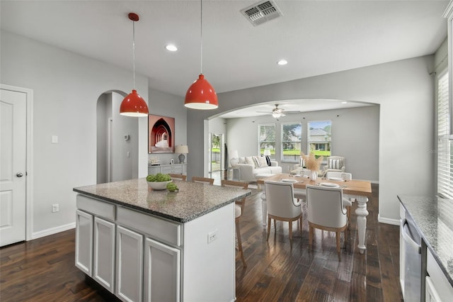 kitchen featuring dark stone counters, a kitchen island, white cabinetry, dark hardwood / wood-style floors, and pendant lighting