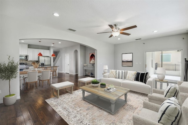 living room featuring dark hardwood / wood-style flooring, a textured ceiling, and ceiling fan